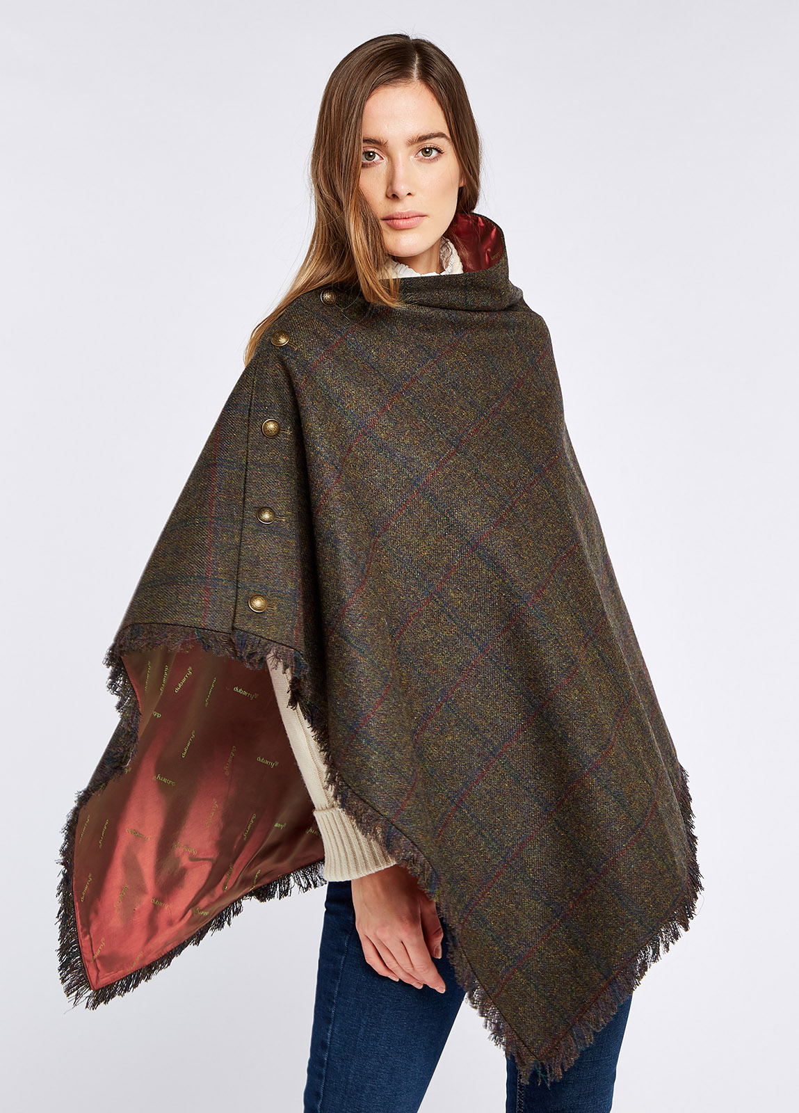 Woman modelling Hazelwood Tweed Hemlock Poncho from an angle with functional button detail on one side and fabric fringe. 