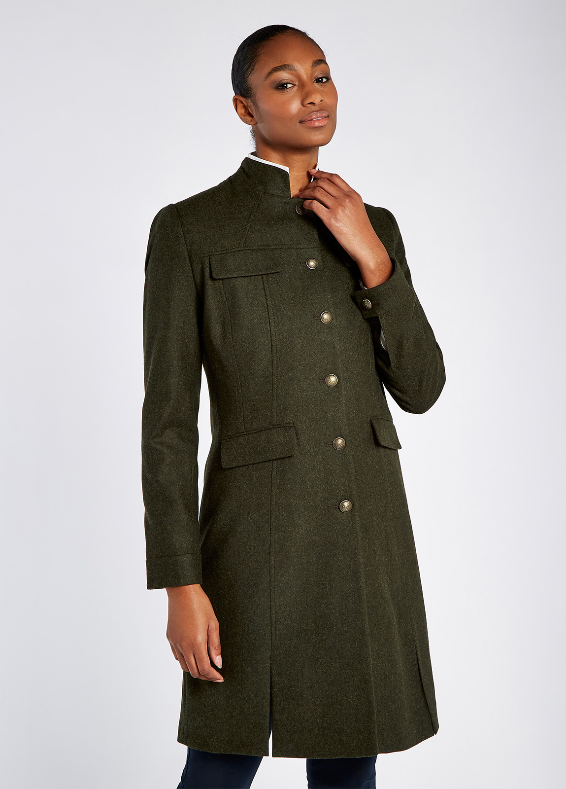 A woman modelling Dubarry women's Coolepark Tweed Loden Coat. A coat with a mandarin collar, four pocket flaps and button front style.
