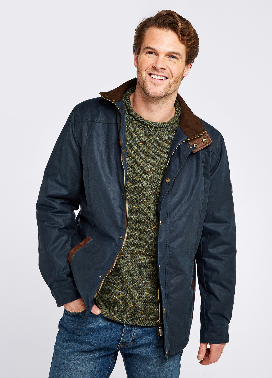 Waist up view of a male model wearing a Dubarry Carrickfergus waxed jacket, ocean blue coloured with a standing collar and buttons along the full zip, the model is wearing the jacket open showing the lighter brown inside collar and he is wearing a green j